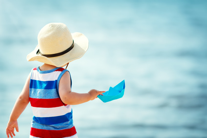 little boy playing at the beach in straw hat